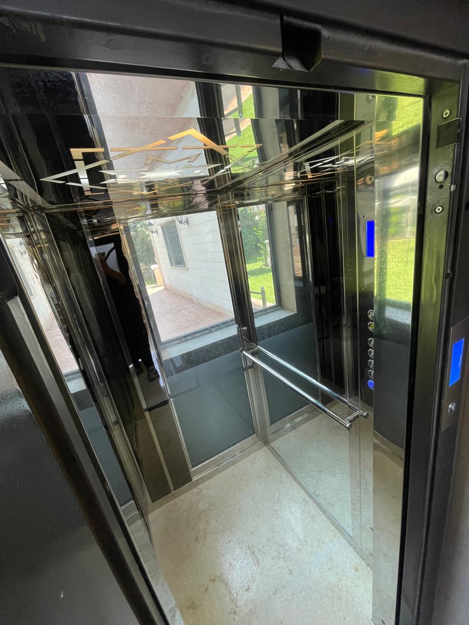Mirrored elevator cabin with glazing, handrails, and decorative ceiling lighting