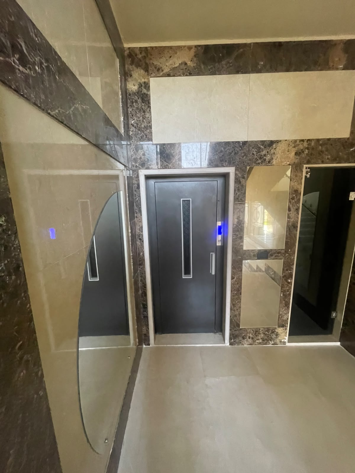 Completed elevator entrance set within a marble-finished residential lobby