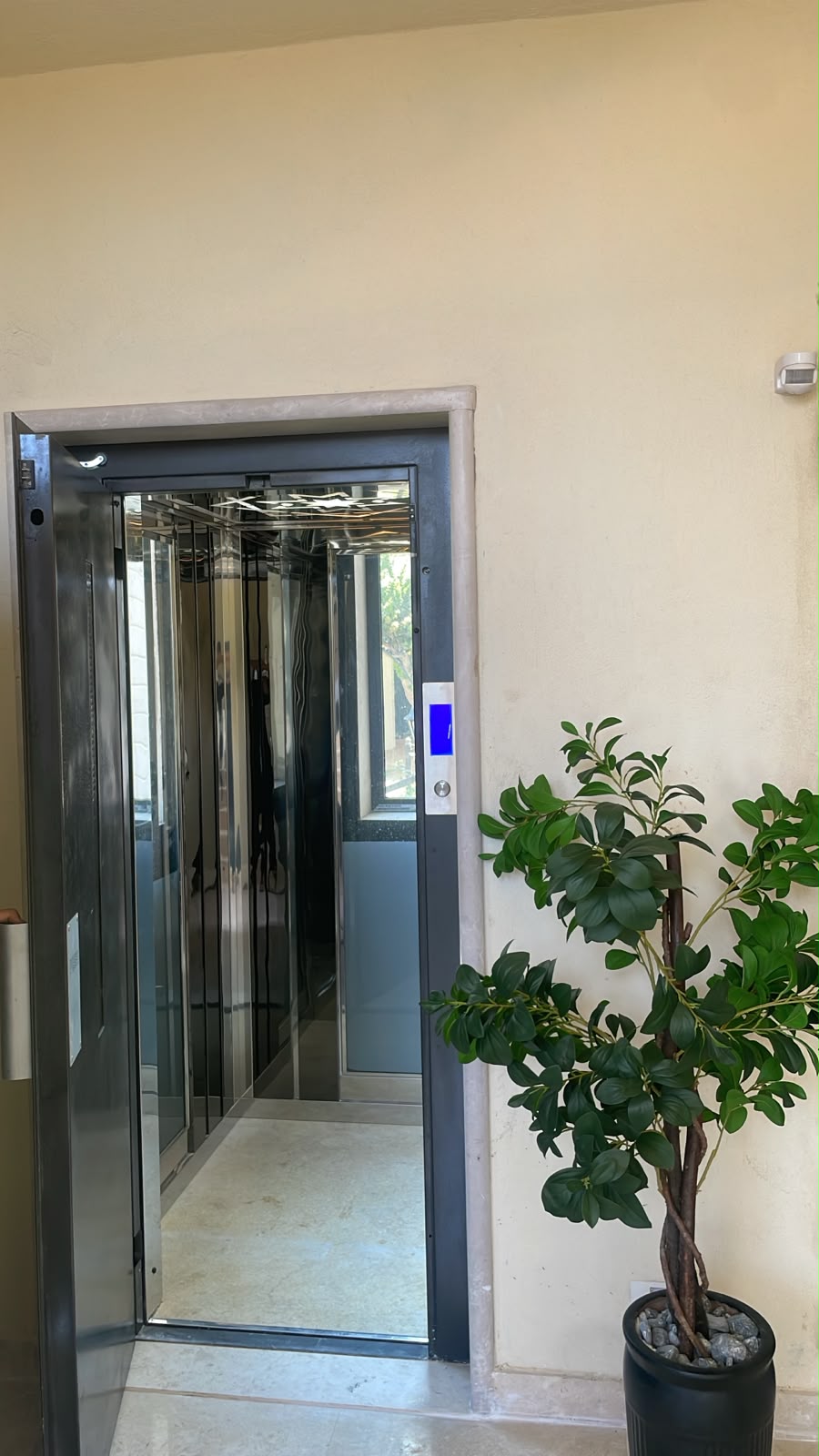 Wide view of the open residential elevator and mirrored cabin